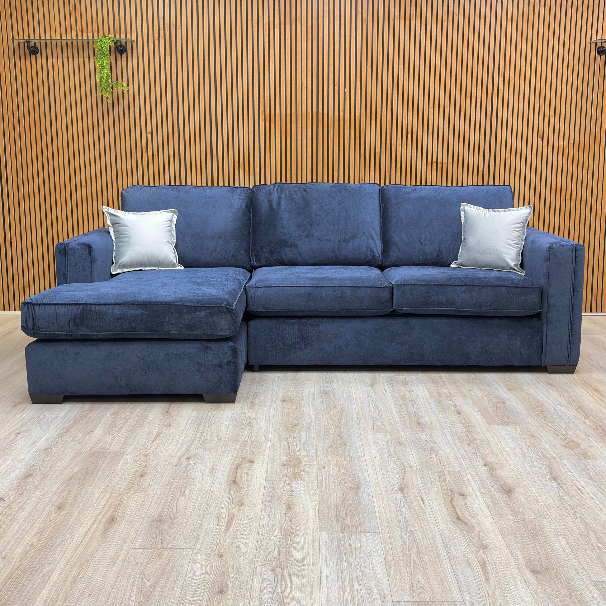 Lifestyle shot of the navy blue 'Chelsea' corner sofa in a bright living room, showcasing its generous seating.