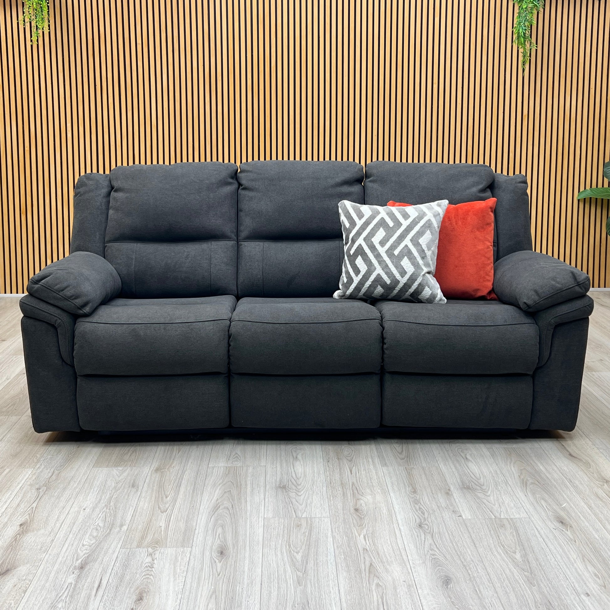 Three-quarter studio perspective with the outer seats fully extended in a relaxing recline, demonstrating the raised footrests and comfortable reclining angle.