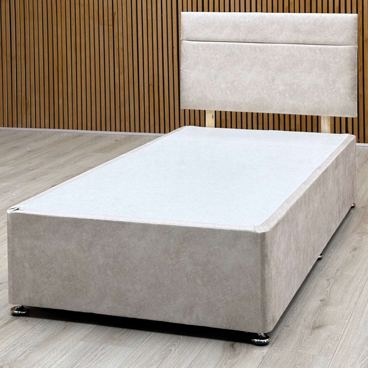 Alfie beige velvet single divan base and headboard against a slatted wooden wall on a light oak floor