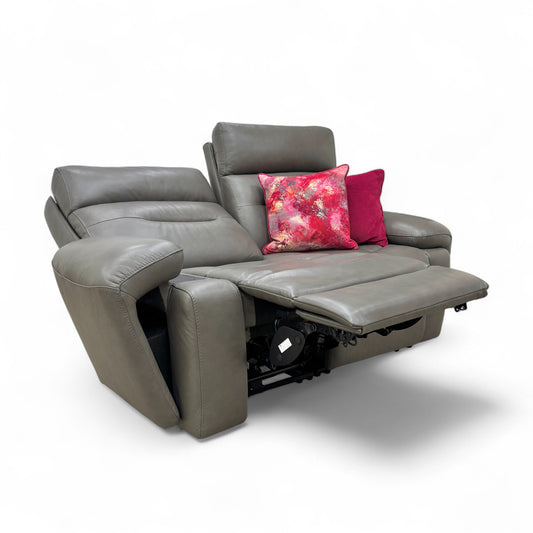 Gray recliner sofa with floral and solid red pillows on a white background