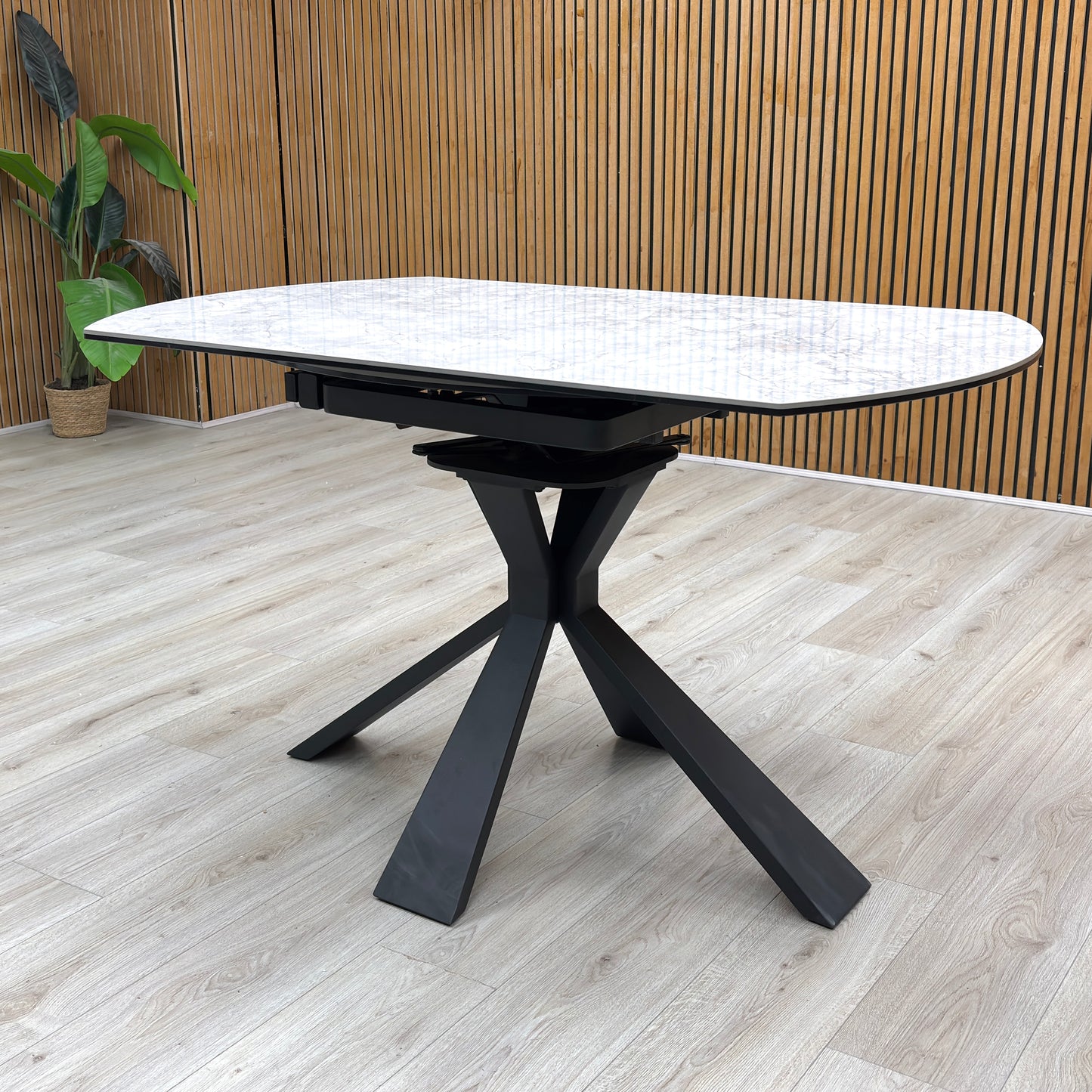 Lifestyle view of the Crete dining table in its compact round form, showcasing the durable textured stone finish and the architectural geometric leg design.