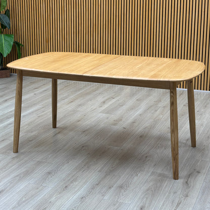 Stockholm light oak extending dining table against a slatted wooden wall on a grey wood-effect floor