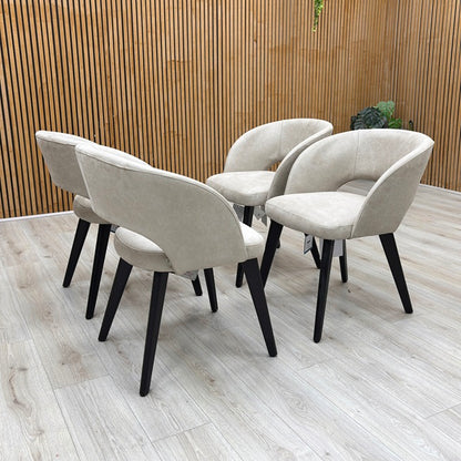 Lifestyle view of a Goya dining chair, showcasing the understated glam style, comfortable low-back silhouette, and dense foam seat cushioning.