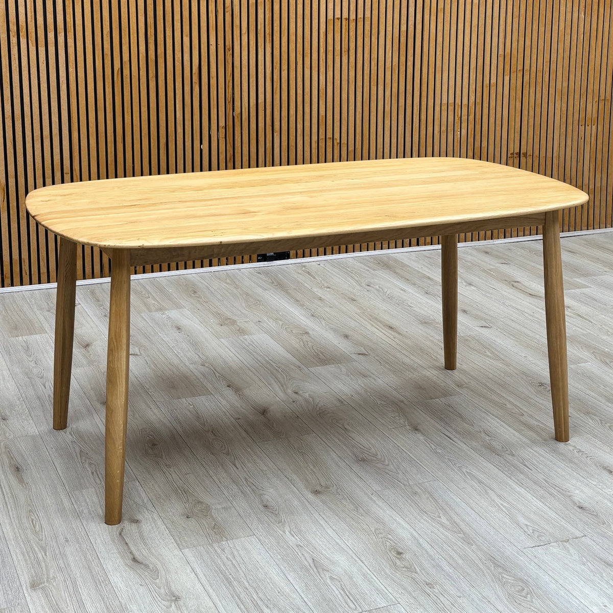 Stockholm light oak solid oak dining table against a slatted wooden wall on a light oak floor