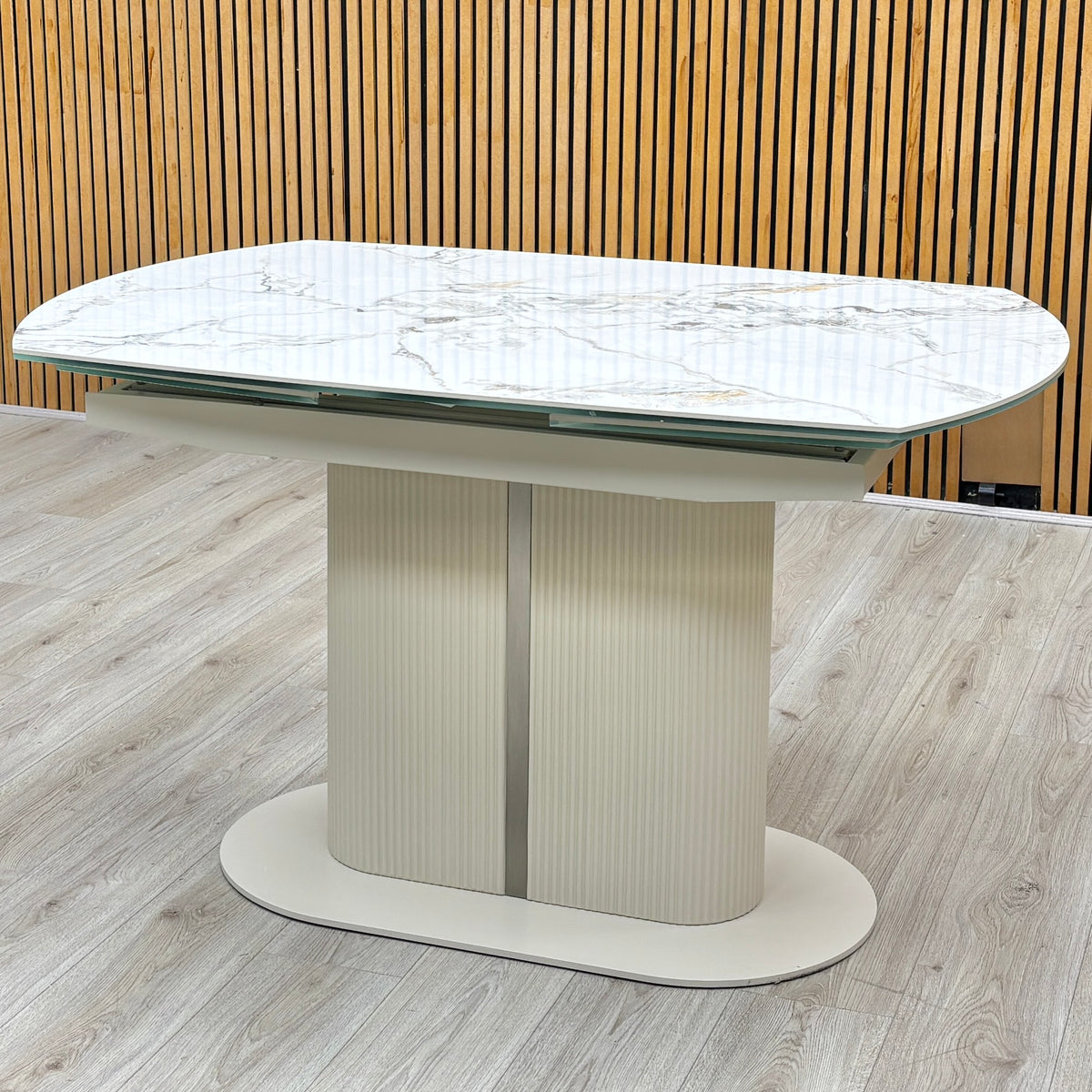 Avorio ceramic top swivel extending dining table closed, against a slatted wooden wall on a light oak floor