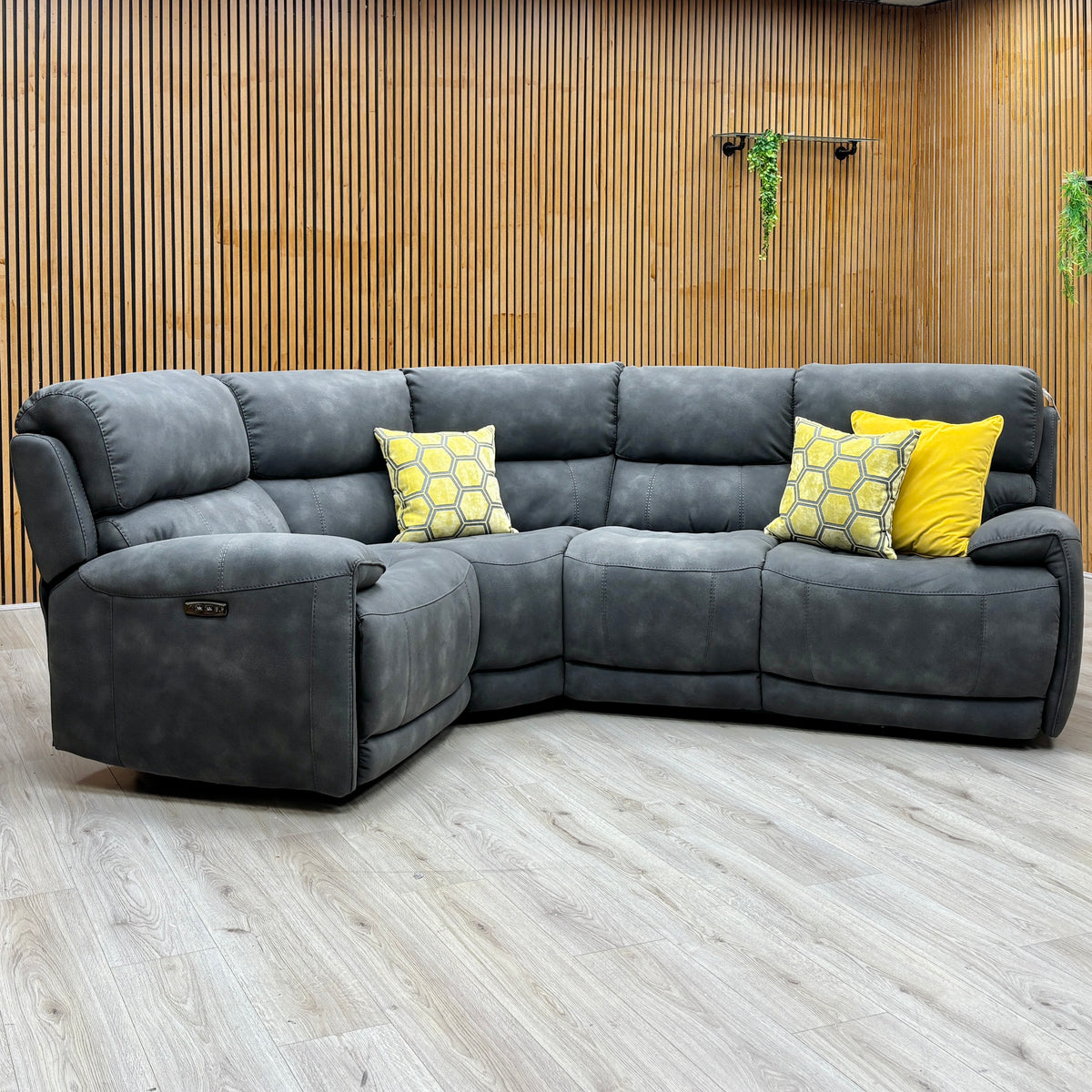 Link charcoal grey suede fabric power recliner sofa against a slatted wooden wall with the left footrest raised