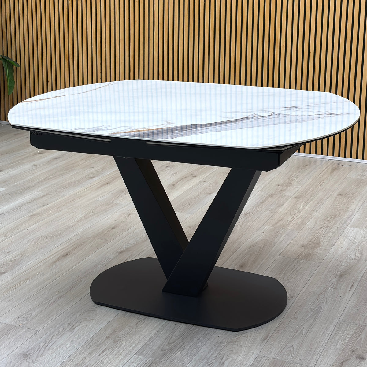 Julio Fiorentino marble ceramic extending dining table on a black V base against a slatted wooden wall