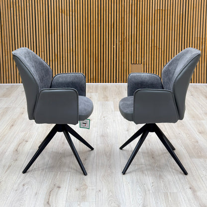 Julio anthracite grey faux leather pair of swivel dining chairs facing each other against a slatted wooden wall