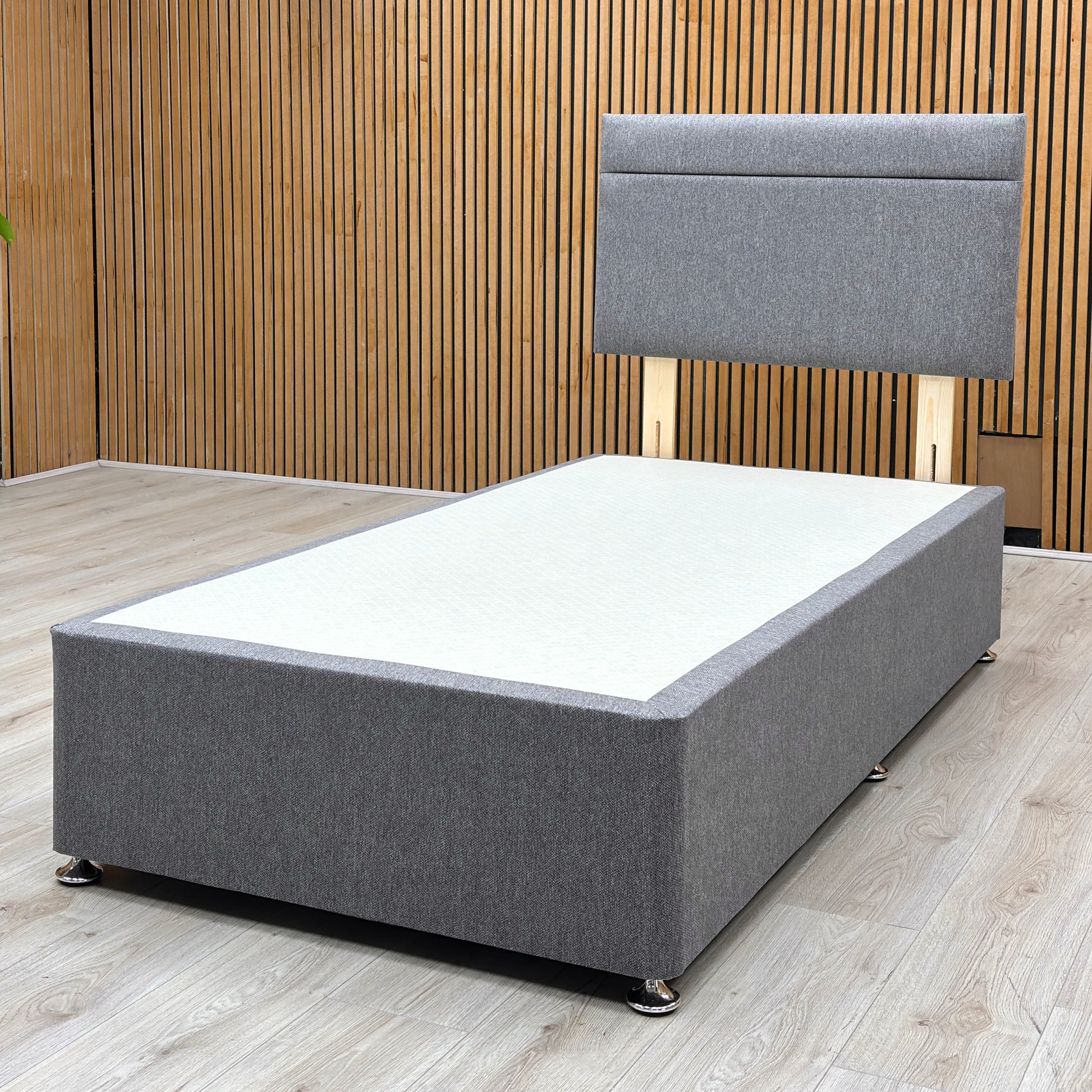 Lifestyle view of the single divan bed, emphasizing the deep under-bed storage drawers fully extended on smooth glides, built into the side of the charcoal fabric base.