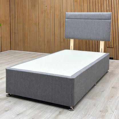 Lifestyle view of the single divan bed, emphasizing the deep under-bed storage drawers fully extended on smooth glides, built into the side of the charcoal fabric base.
