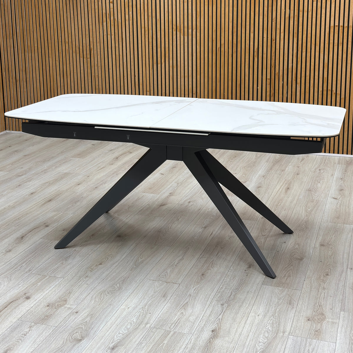 Carrera ceramic top large dining table closed against a slatted wooden wall on a light wood floor