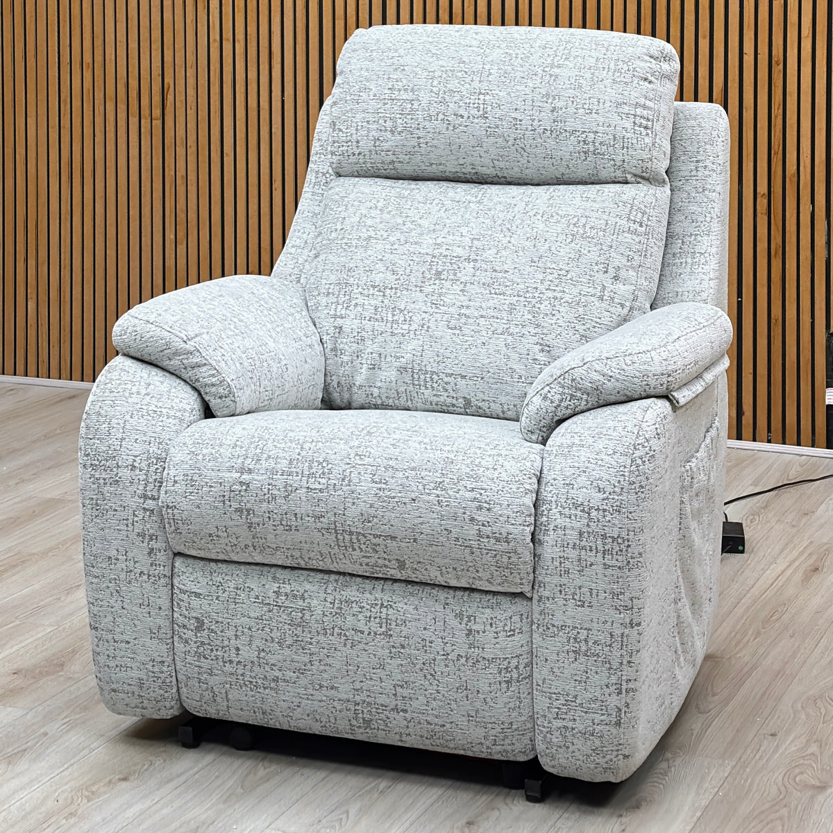 G Plan Kingsbury mist grey fabric lift and rise recliner chair against a slatted wooden wall on a light oak floor