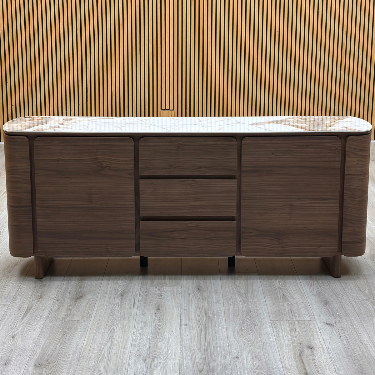 Front view of the Mekong marble effect ceramic top 2 door 3 drawer sideboard against a slatted wooden wall