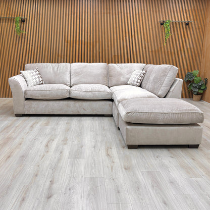 Lifestyle shot of the Rosie corner sofa in mink fabric, highlighting the generous chaise extension and plush cushioning.