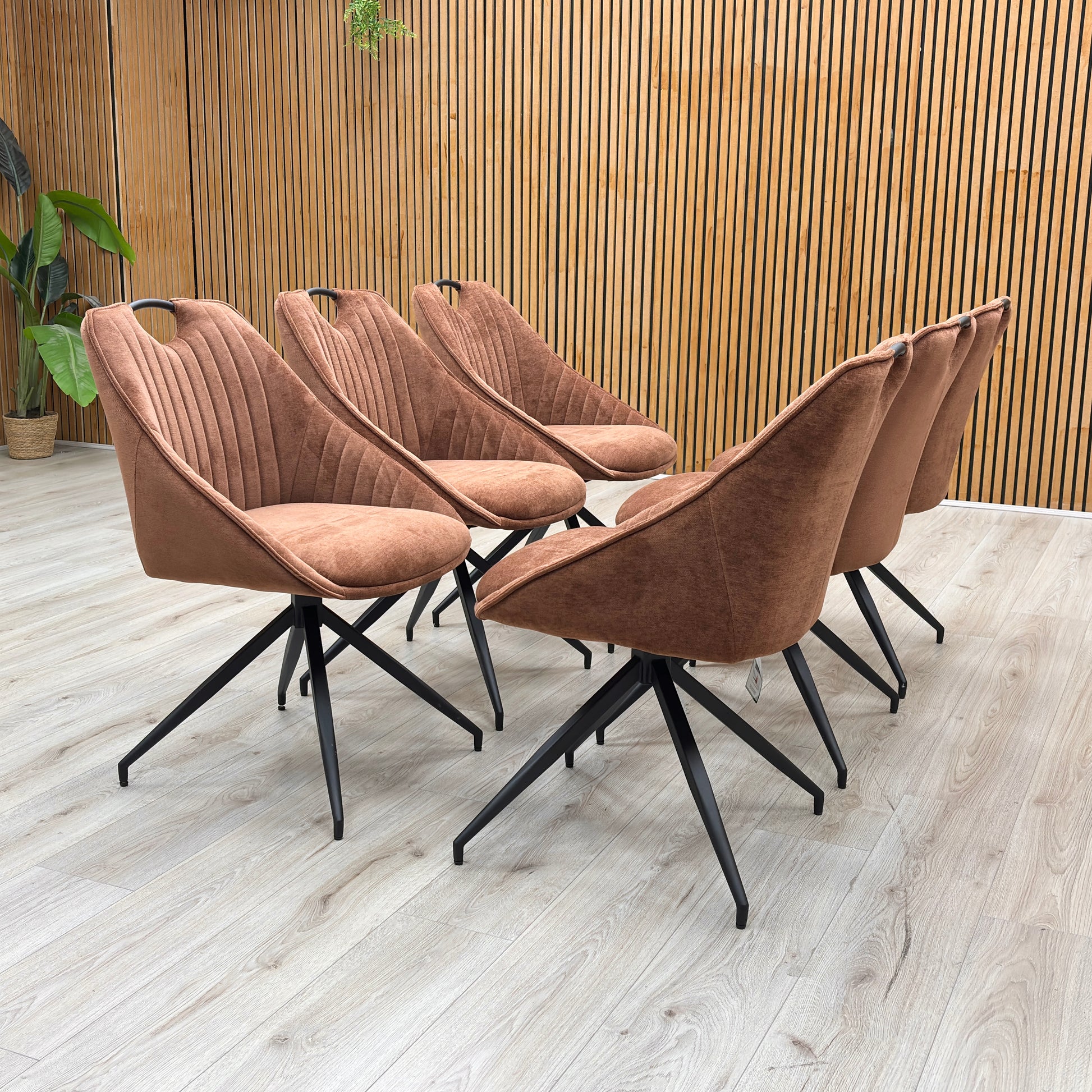 Lifestyle view of the ‘Jai’ swivel chair, emphasizing the deeply padded seat cushion and the warm, high-contrast pop of color from the rust orange textured fabric.