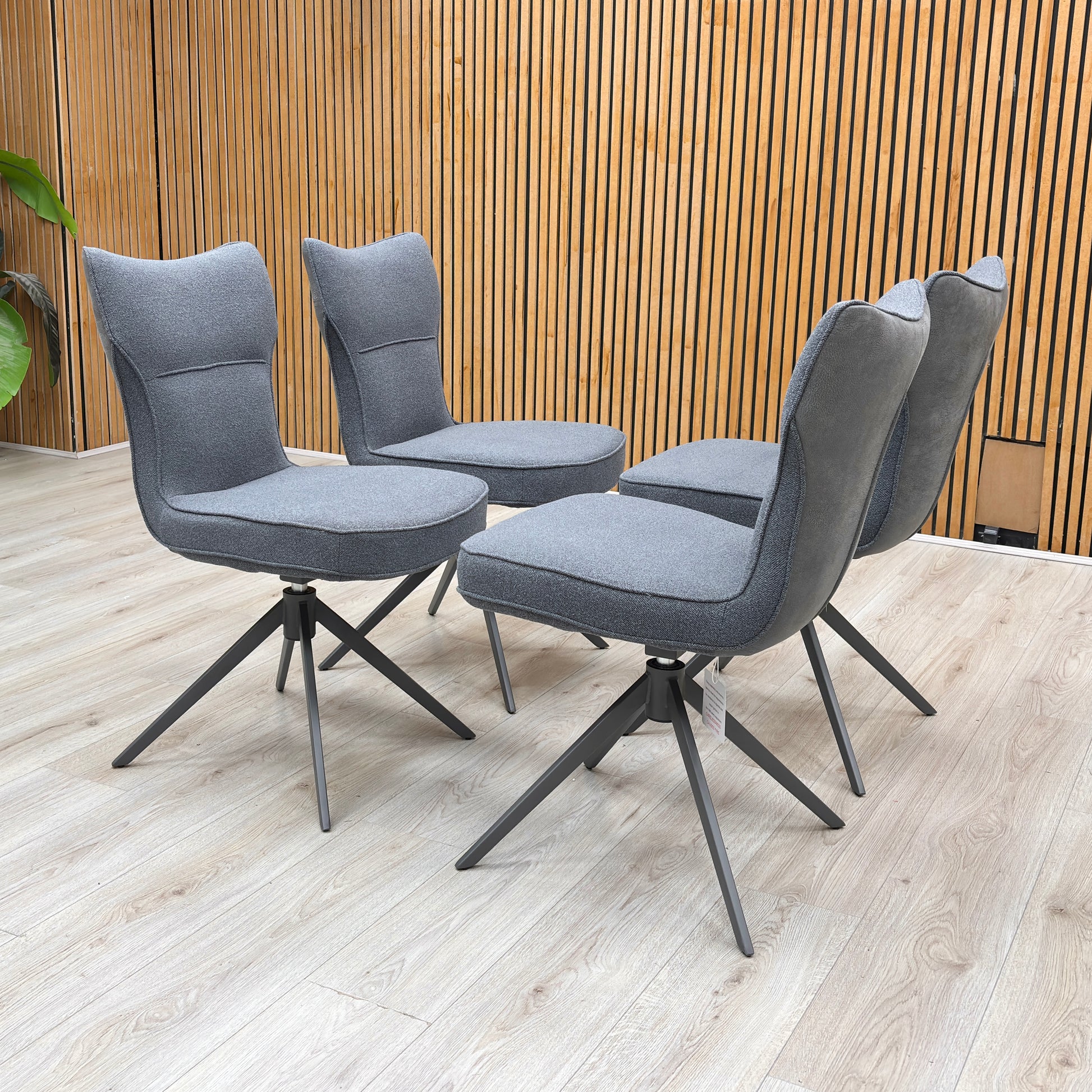 Lifestyle view of the ‘Carrera’ swivel chair, emphasizing the deeply padded seat cushion and the elegant monochromatic look of the neutral grey fabric with dark legs.