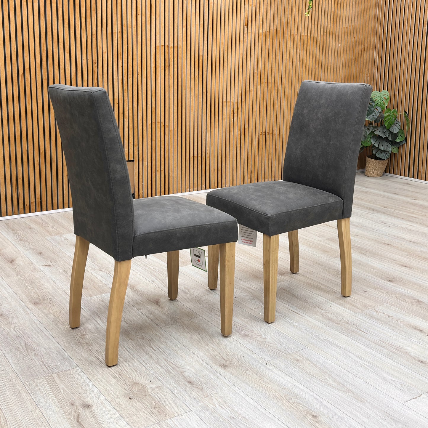Lifestyle view of the ‘Augusta’ dining chair, emphasizing the comfortable deeply padded seat cushion and the elegant monochromatic look of the grey upholstery with dark legs.
