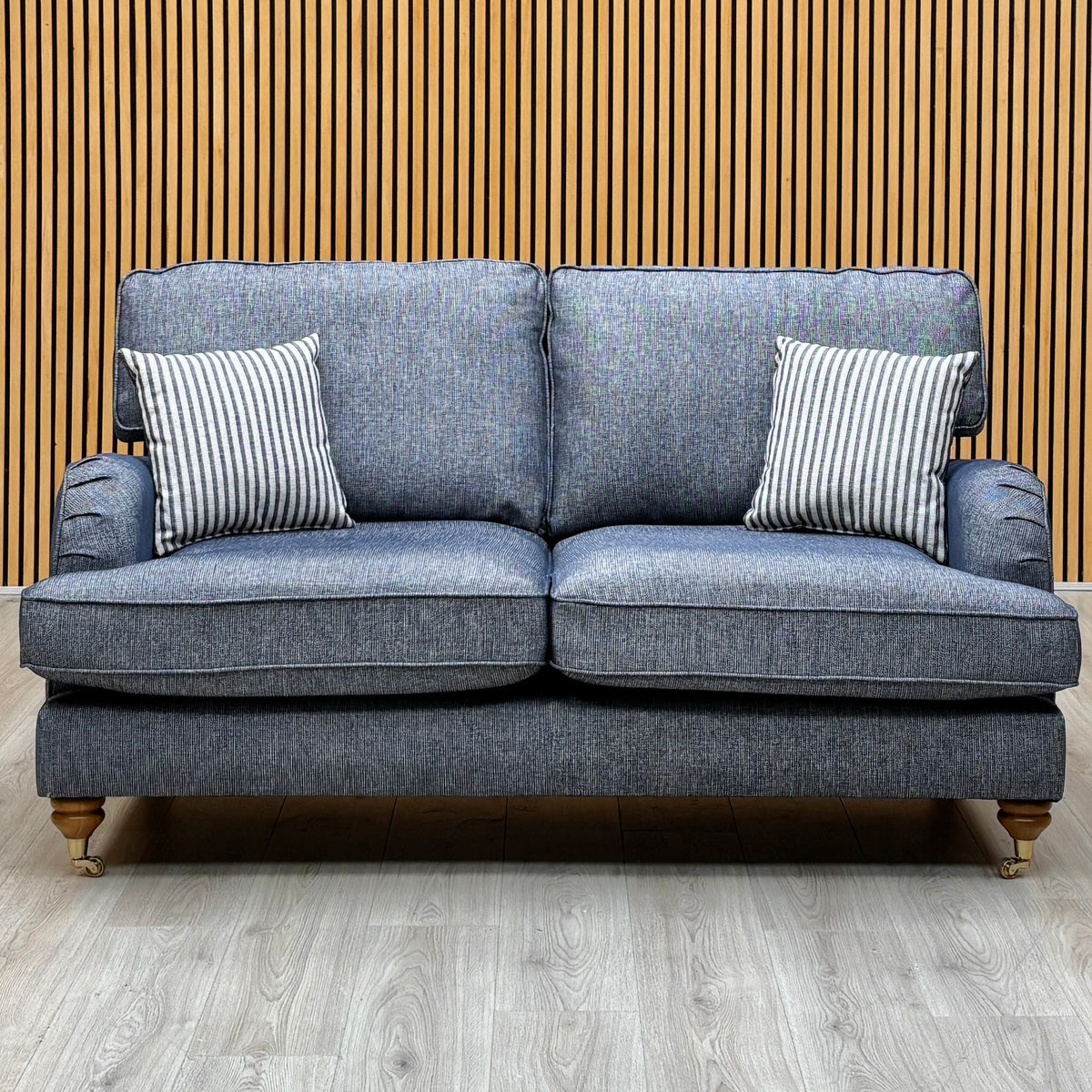 Bay navy blue fabric 2 seater sofa against a slatted wooden wall on a pale wood floor