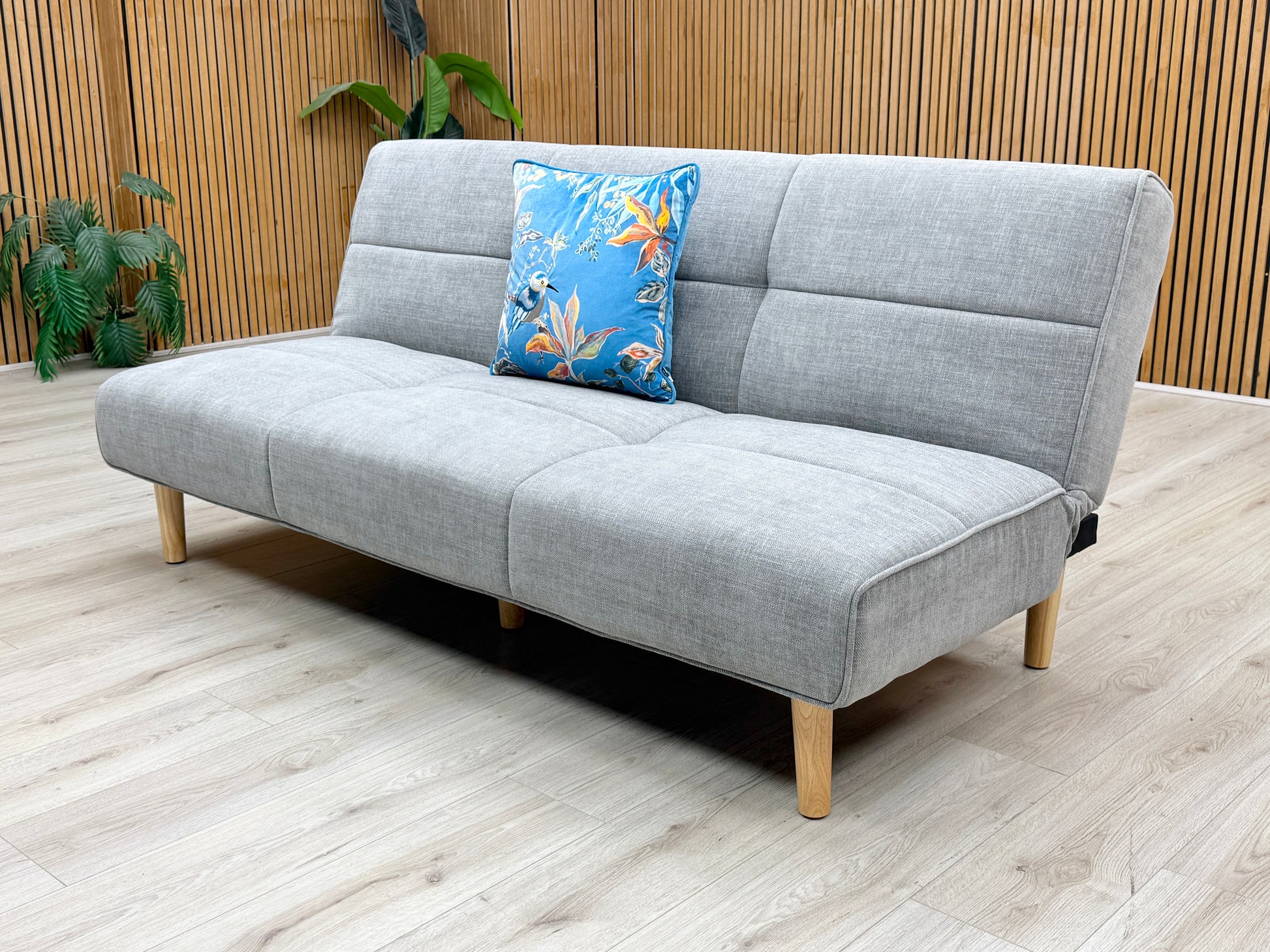 Lifestyle view of the ‘Miyagi’ futon sofa bed, showcasing the wide, plush seating surface and the textured weave of the mist grey upholstery.