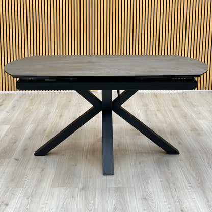 Front view of the Raul titanium grey ceramic 160cm dining table on a black spider base, on a light oak floor