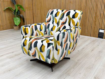 Side view of the ‘Hedingham’ swivel accent chair, emphasizing its plush, deep seat and the bold, colorful artistic pattern of the Audley Terrazzo velvet fabric.