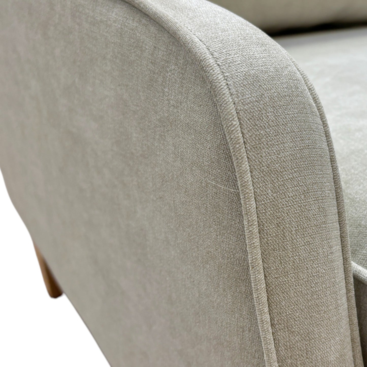 Close-up of a beige upholstered chair armrest with visible stitching.