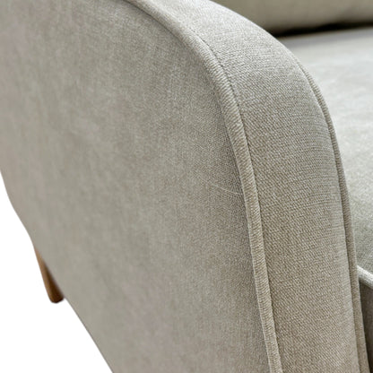 Close-up of a beige upholstered chair armrest with visible stitching.