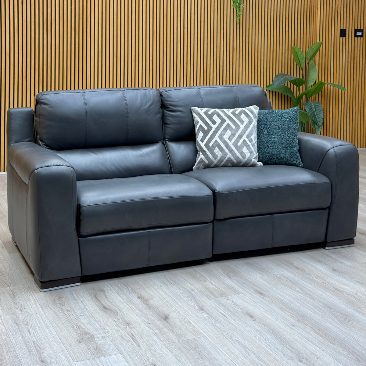 Marinelli Viali grey leather 3 seater power recliner sofa against a slatted wooden wall on a light wood floor