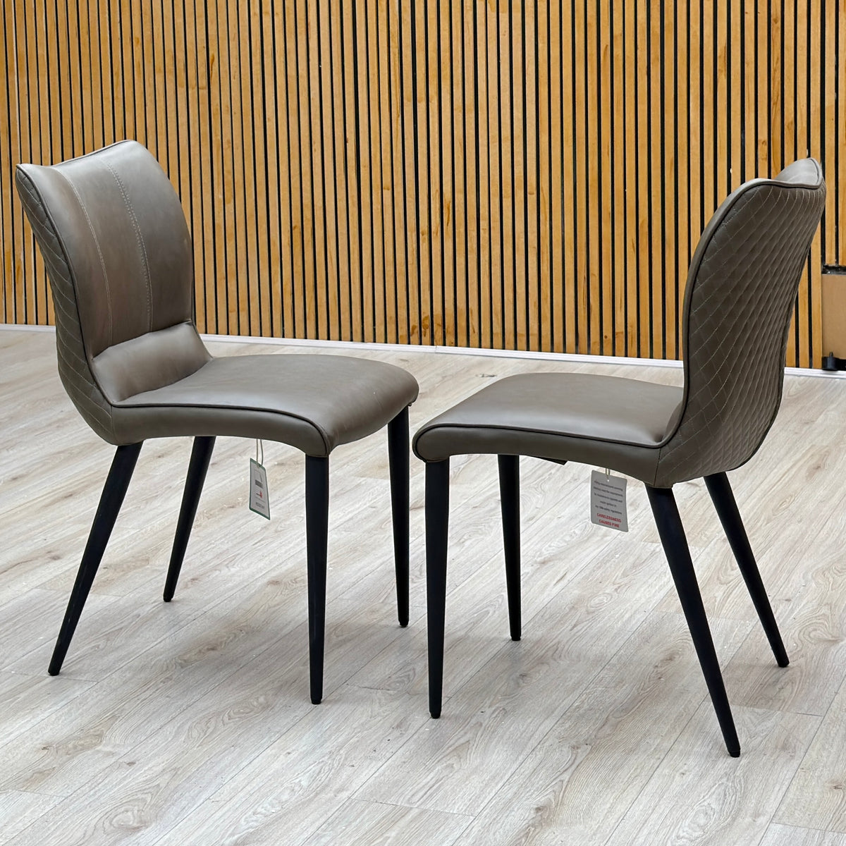 Murcia antiqued olive green pair of dining chairs photographed on a light floor against a slatted wall