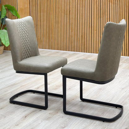 Bodahl Loki olive green fabric pair of cantilever dining chairs against a slatted wooden wall on a light wood floor