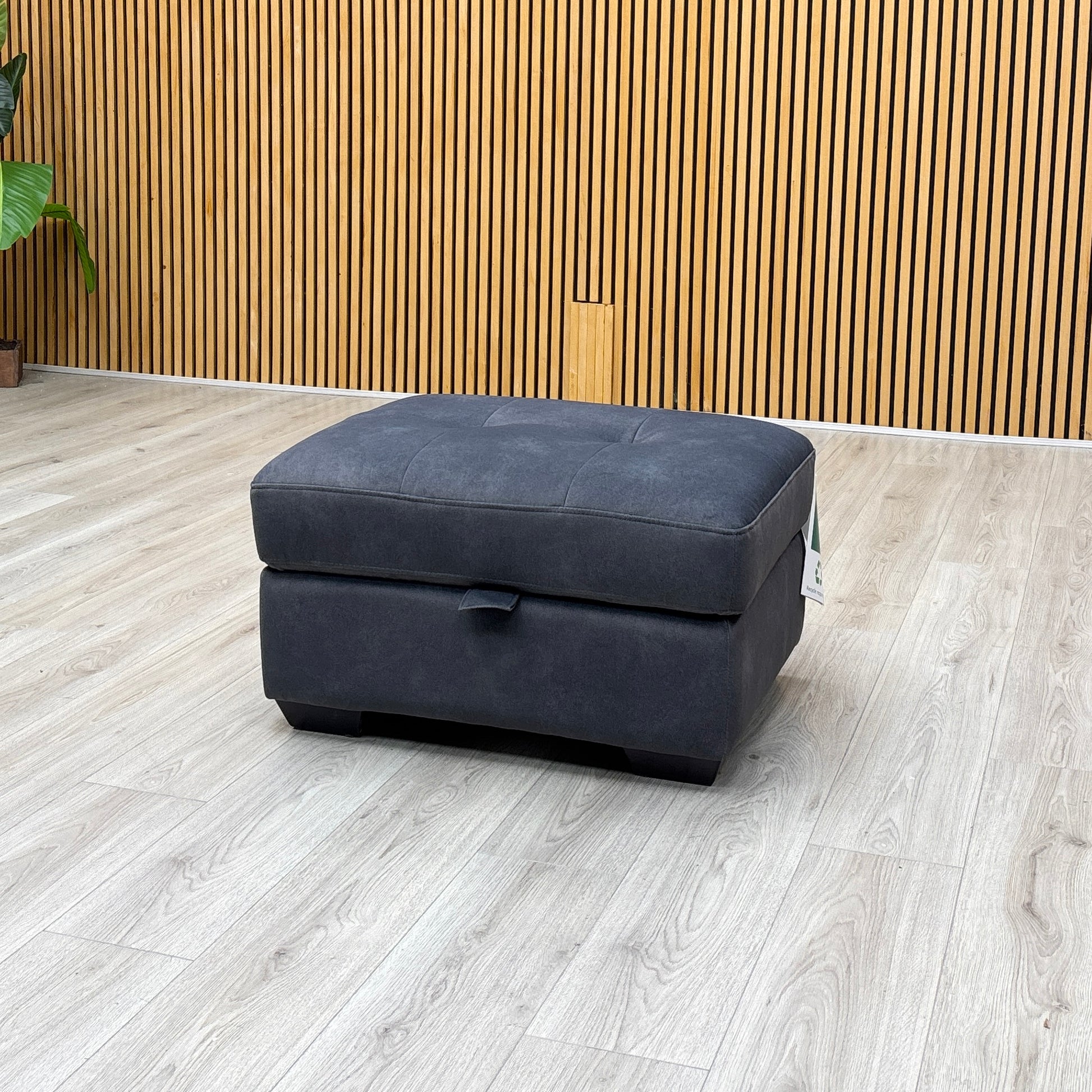 studio angle showcasing the rectangular charcoal grey ottoman with its top cushion lid fully open, revealing a deep internal storage compartment.