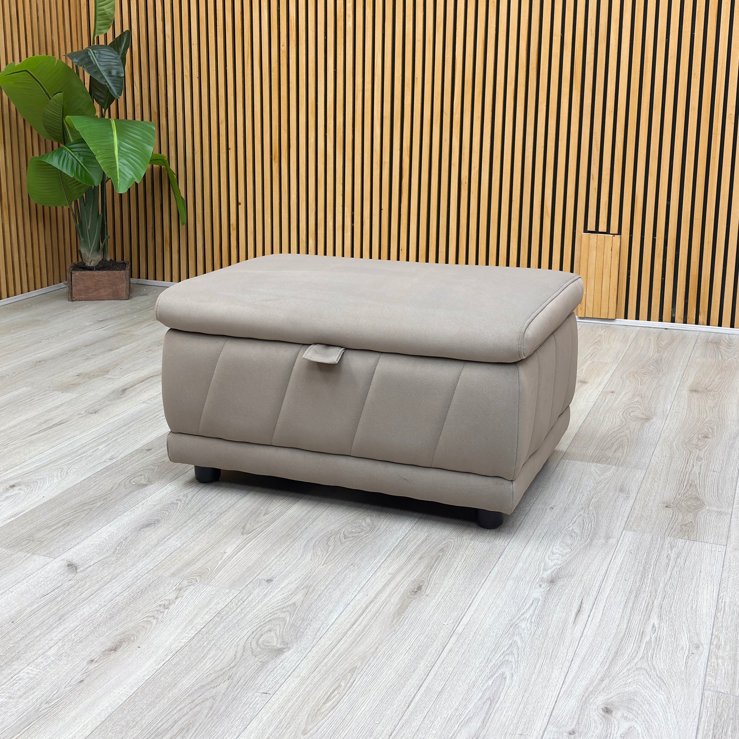 studio angle showcasing the rectangular footstool with its top cushion lid fully raised, revealing a spacious internal storage compartment