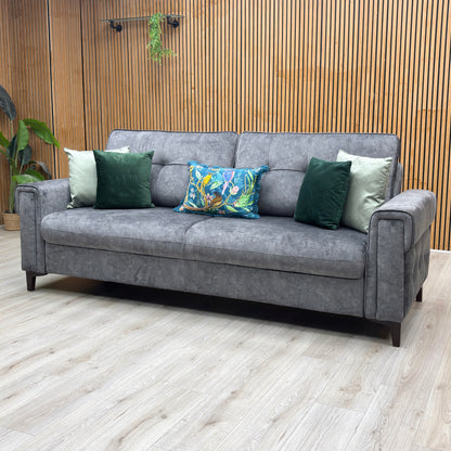 Lifestyle view three-quarter angled view of the Zoom dark grey fabric multi-functional sofa bed, highlighting the contemporary block silhouette and compact apartment-living design.