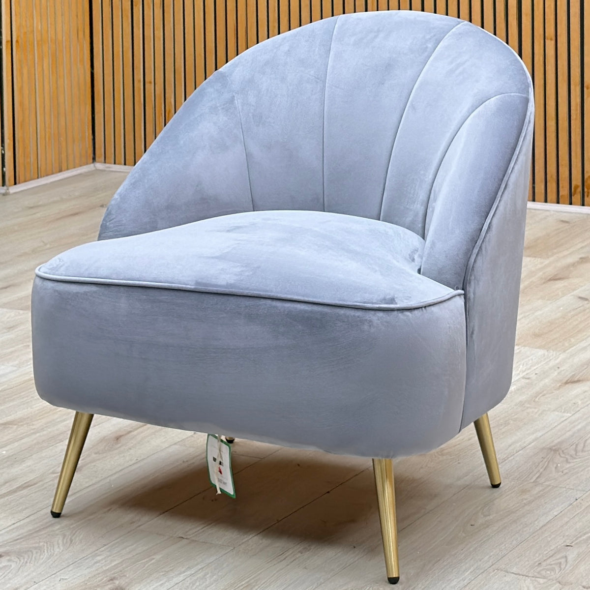 Cali bluish grey velvet accent chair against a slatted wooden wall on a light oak floor