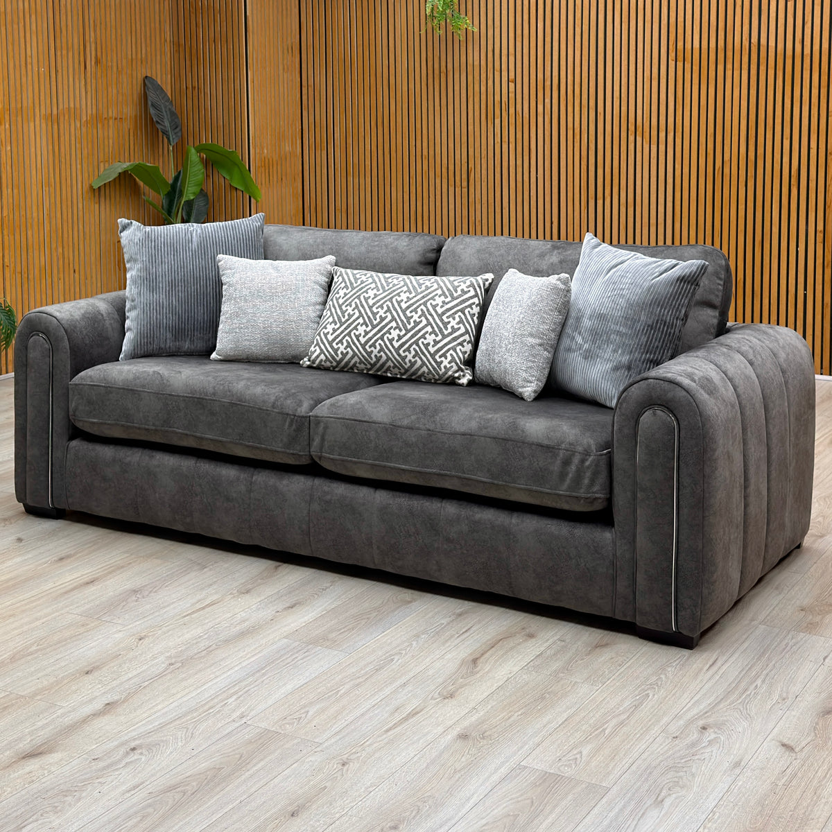 Amara charcoal grey velvet 3 seater sofa against a slatted wooden wall on a pale wood floor