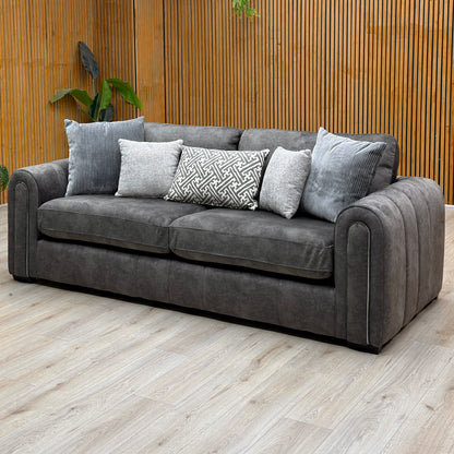 Amara charcoal grey velvet 3 seater sofa against a slatted wooden wall on a pale wood floor