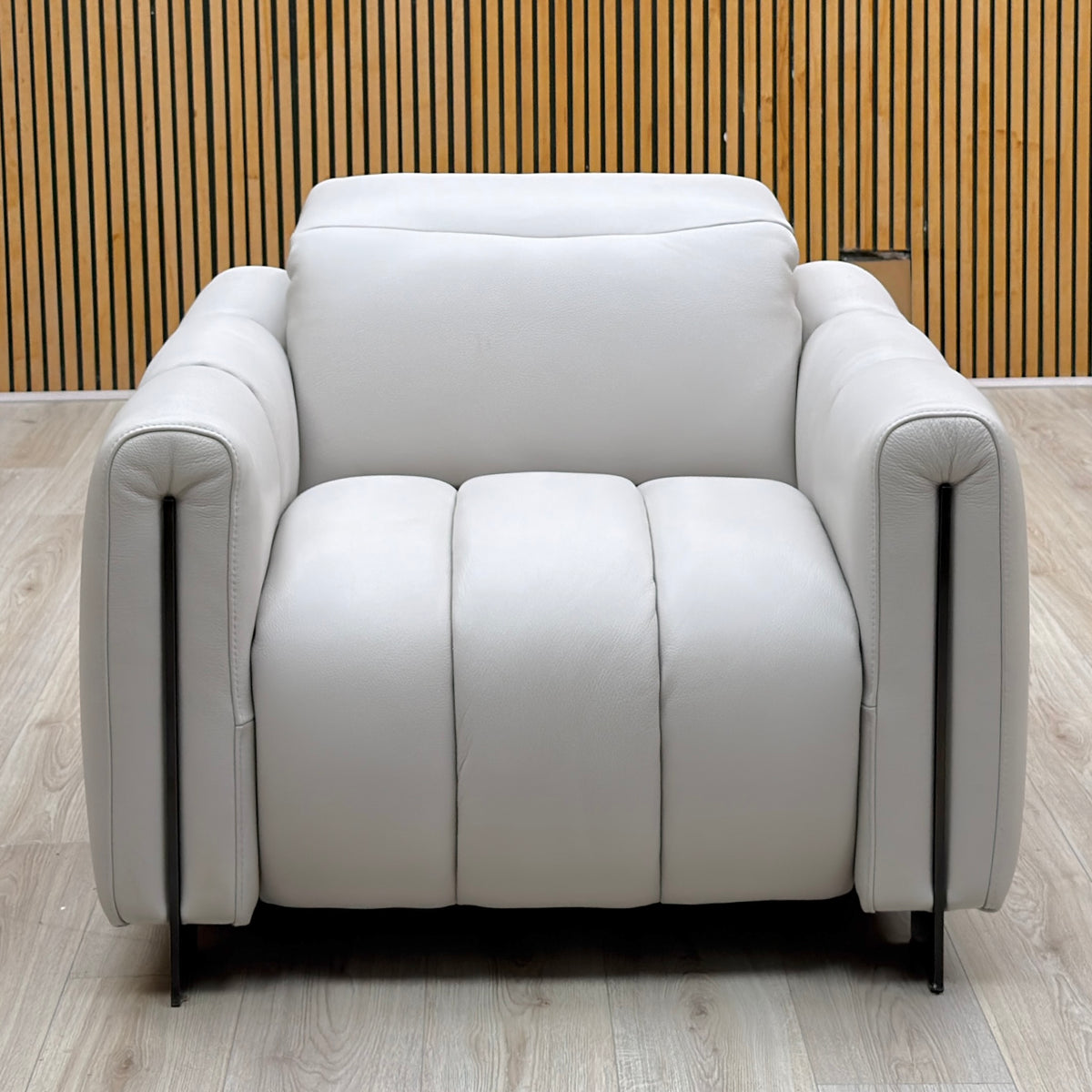 Front view of the Giorgio light grey leather armchair photographed against a slatted wooden wall