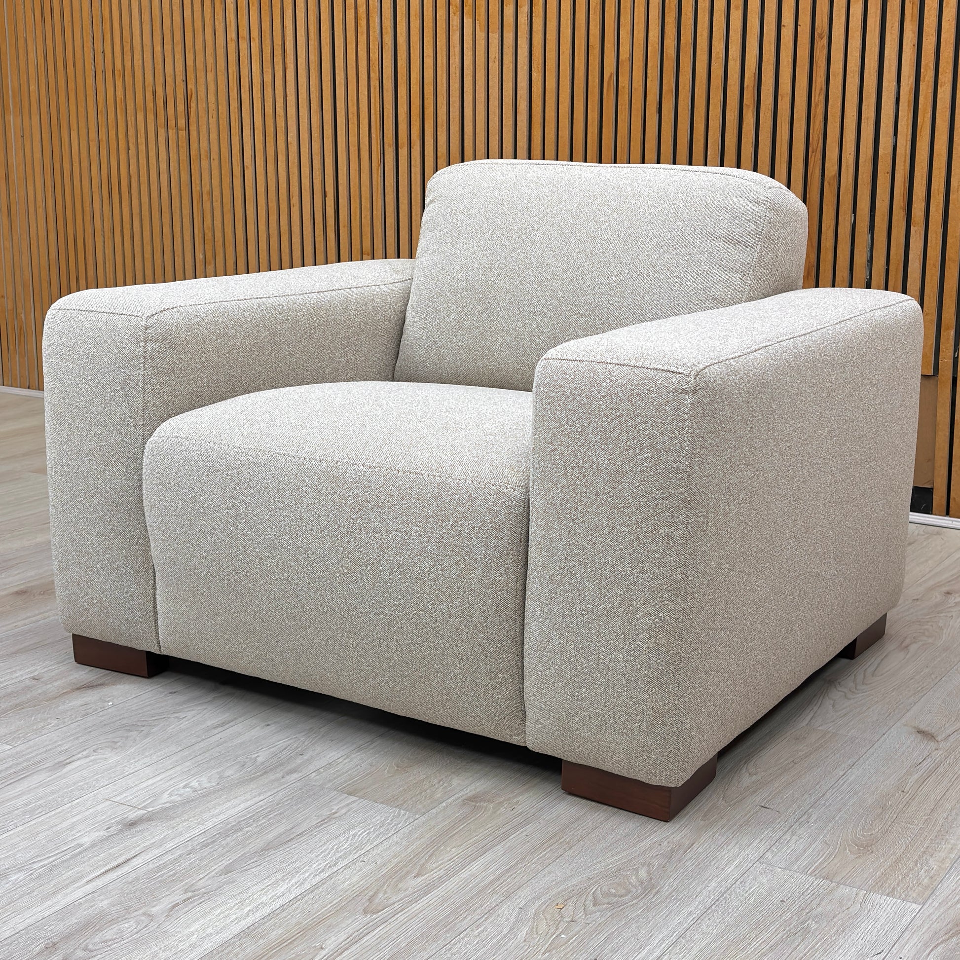 shot of the ‘Cortes’ natural fabric armchair, highlighting its structured silhouette and neutral tone