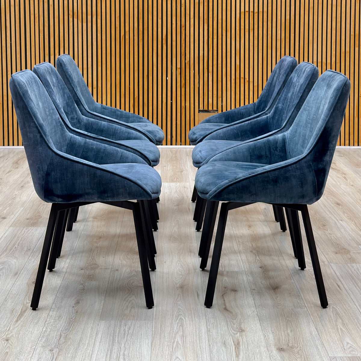 Veja heritage blue velvet set of 6 swivel dining chairs in two facing rows against a slatted wooden wall
