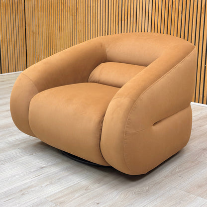 Stylized lifestyle shot of the ‘Joey’ caramel swivel chair showcasing the plush deep-cushioned seat and contemporary curved design.