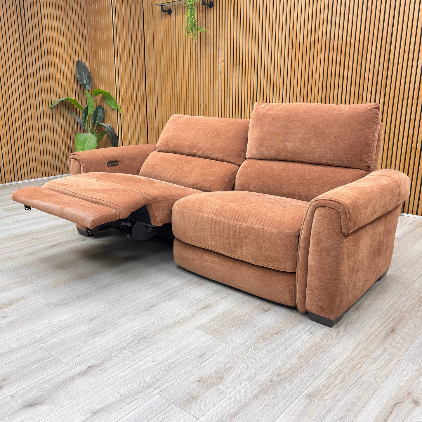 Stylized lifestyle shot of the caramel Nixon sofa in a modern, brightly lit living room.