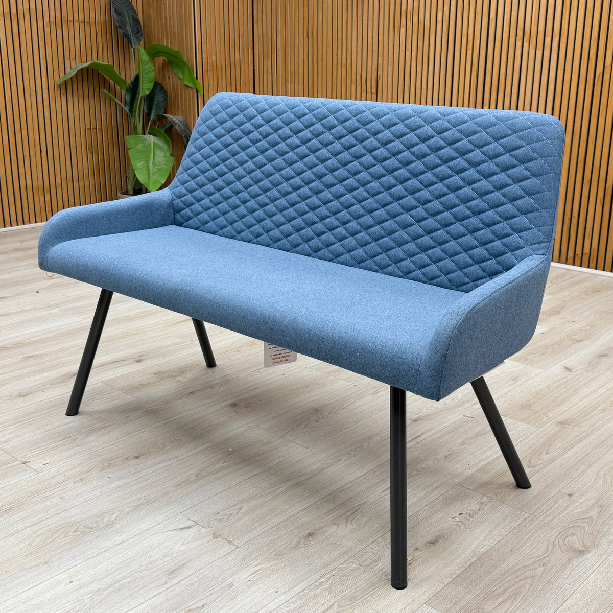 Rocket mineral blue fabric high back dining bench against a slatted wooden wall on a light oak floor