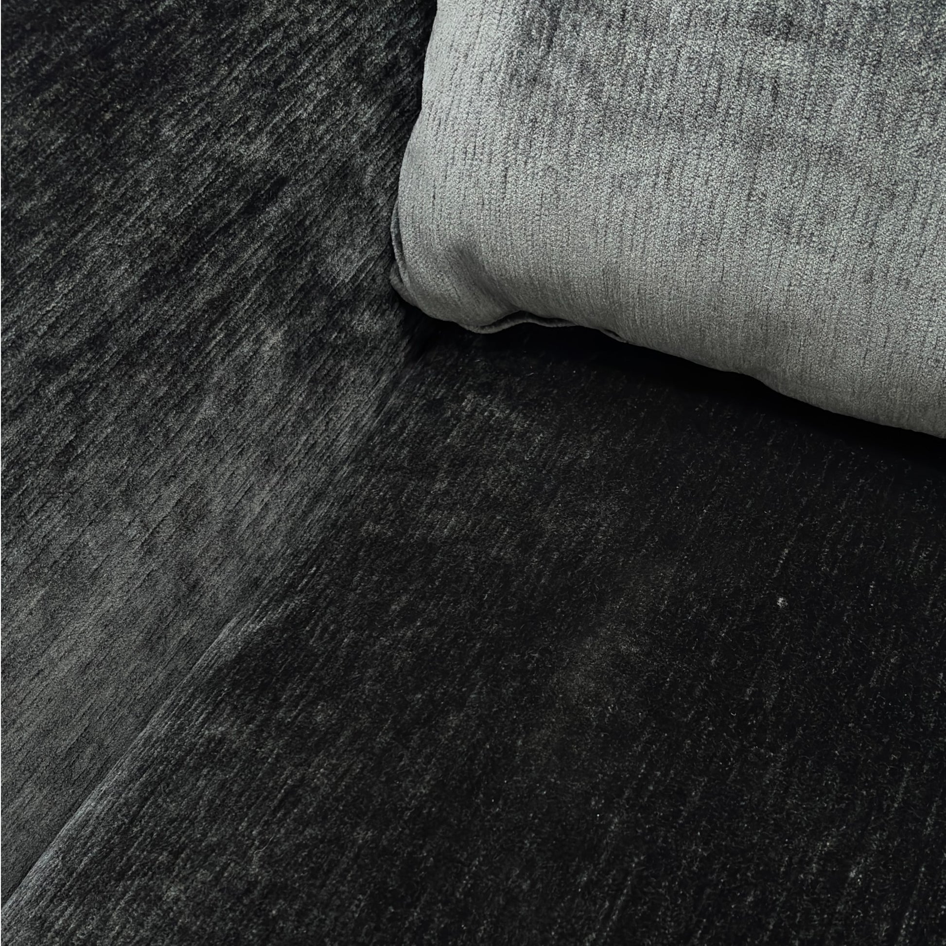 Close-up detail of the soft, dark charcoal grey velvet upholstery on the Maddison sofa.