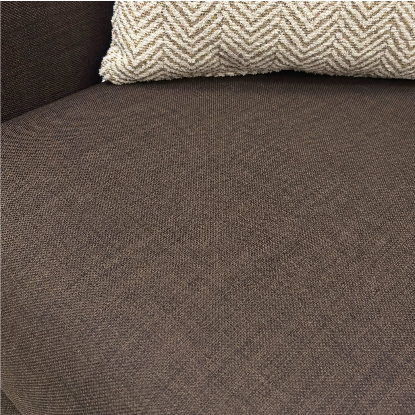 Brown textured fabric surface with a patterned pillow on top