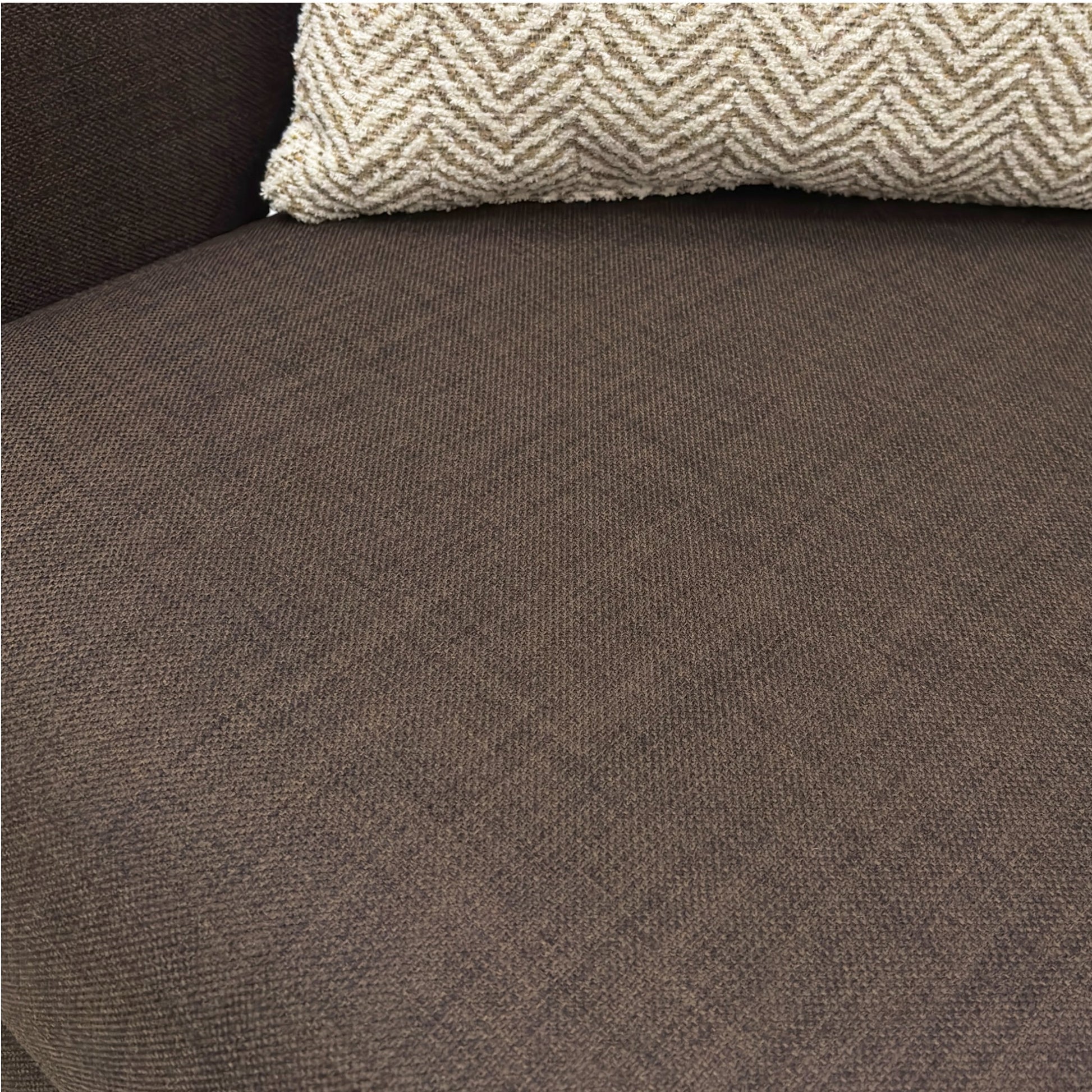 Brown textured fabric surface with a patterned pillow on top