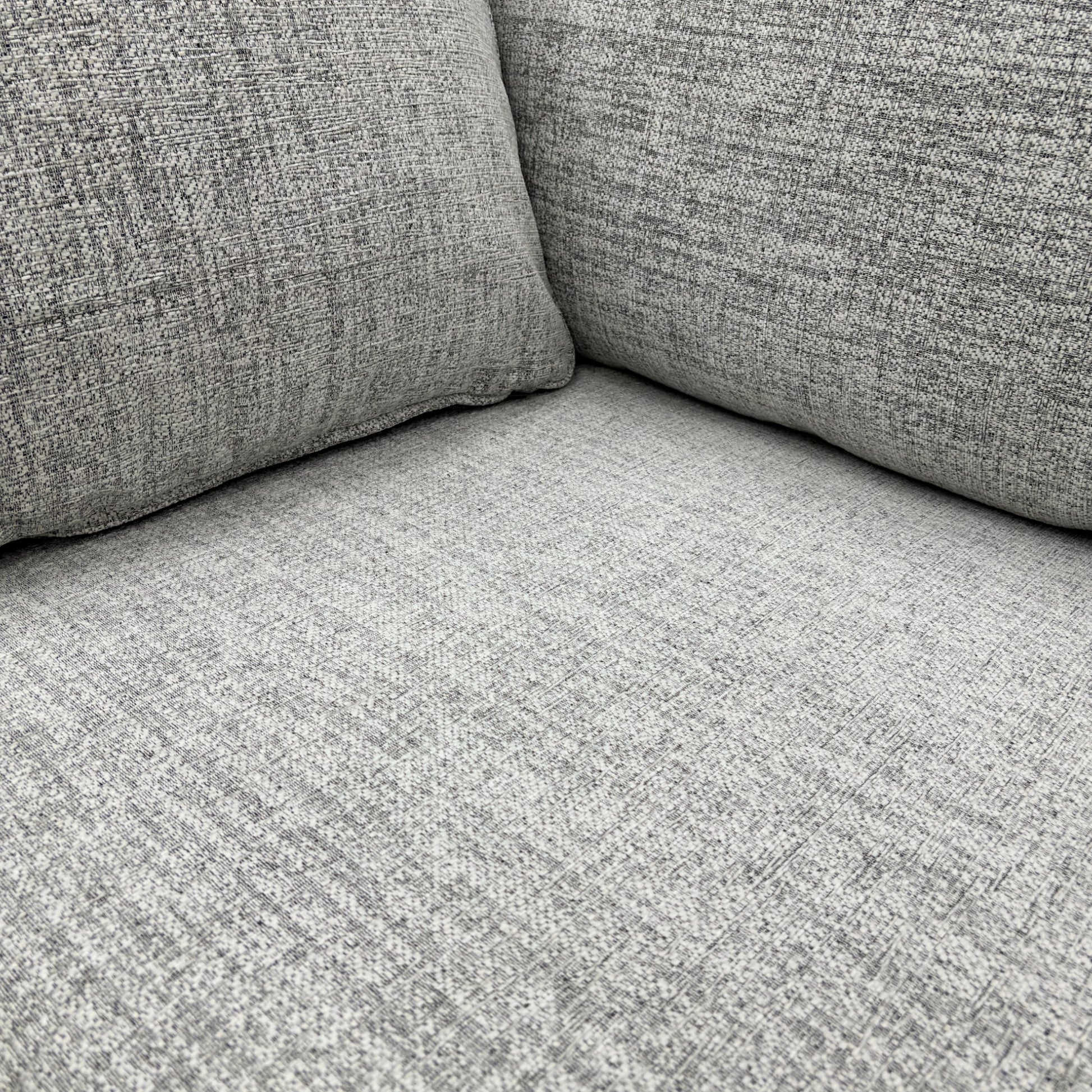Close-up detail of the Sort Grey Woven Fabric upholstery, clearly showing the textured weave and neutral colour of the material.