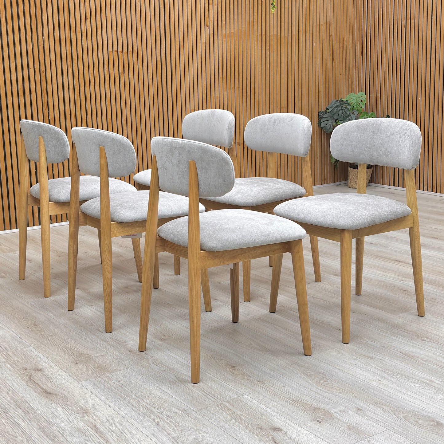 Lifestyle view of the Stockholm dining chair showing the seamless grey fabric wrap and sturdy oak leg attachment.