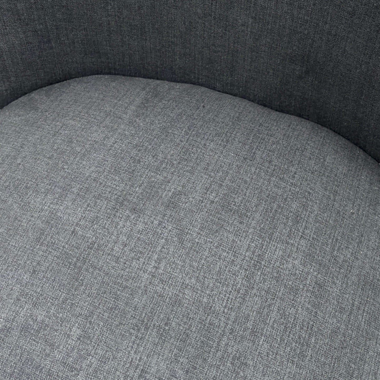 Close-up of a gray upholstered chair seat with a textured fabric finish.