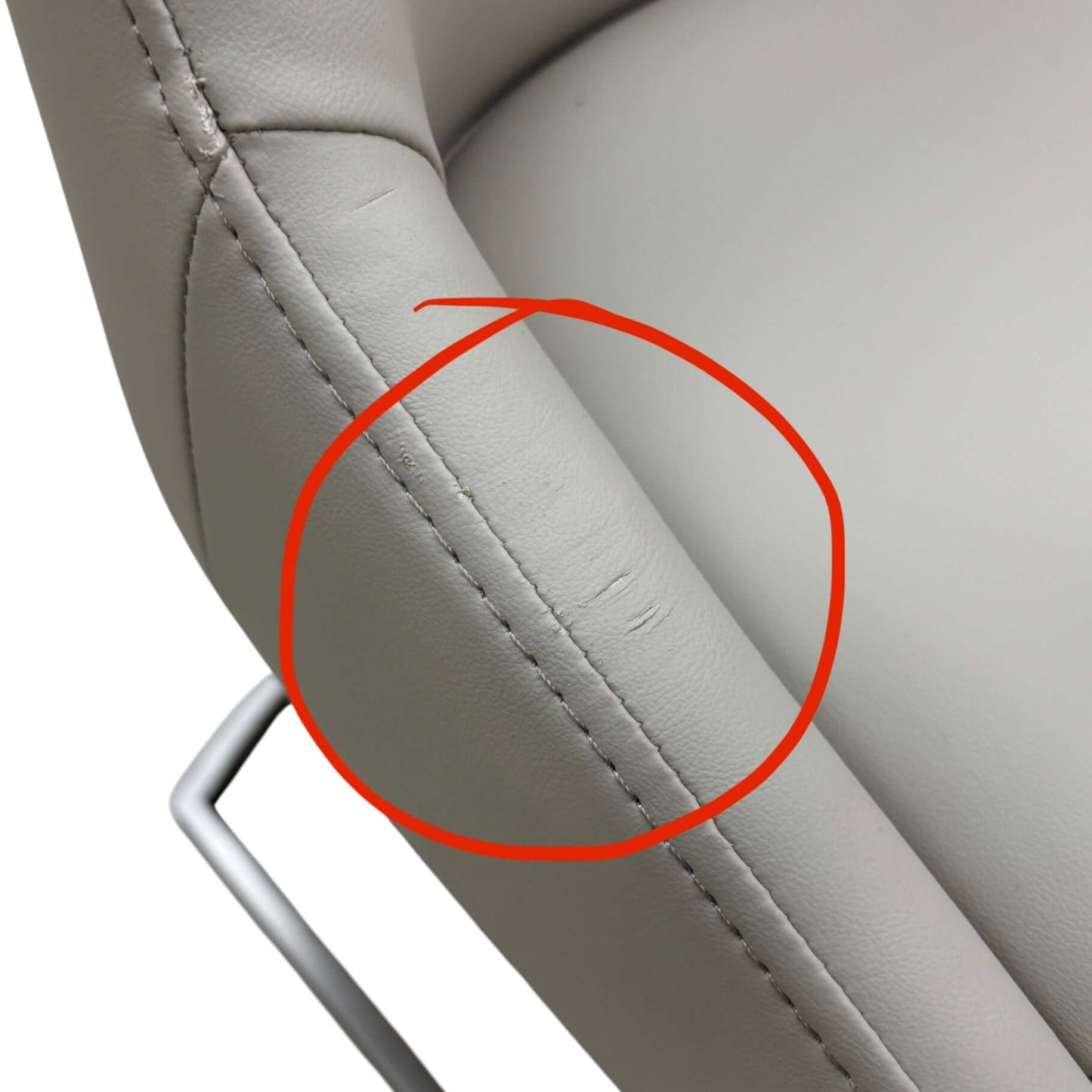 Gray car seat with a red circle highlighting a scratch.