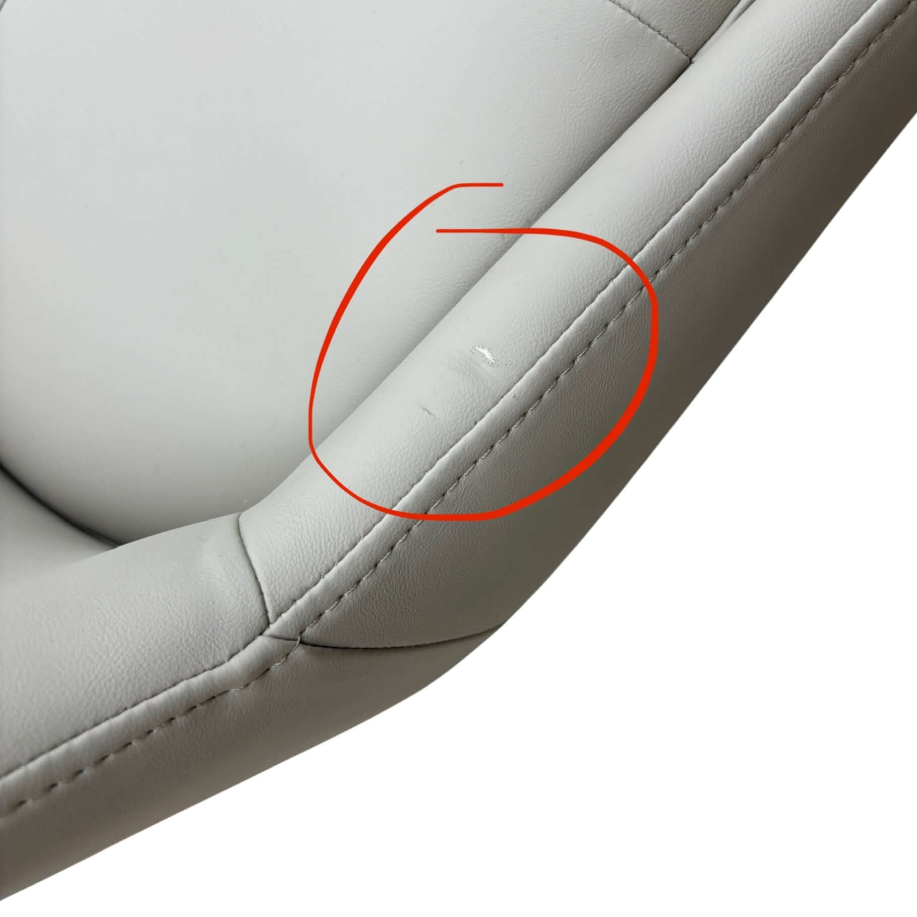 Close-up of a gray leather seat with a red circle highlighting a small imperfection.